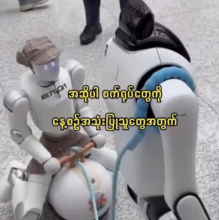 ၂၀၂၆ ခုနှစ် ကမ္ဘာ့ ဉာဏ်ရည်တု ညီလာခံတွင် စက်ရုပ်တစ်ရုပ်က အခြားစက်ရုပ်တစ်ရုပ်ကို လမ်းလျှောက်ခေါ်ဆောင်လာ