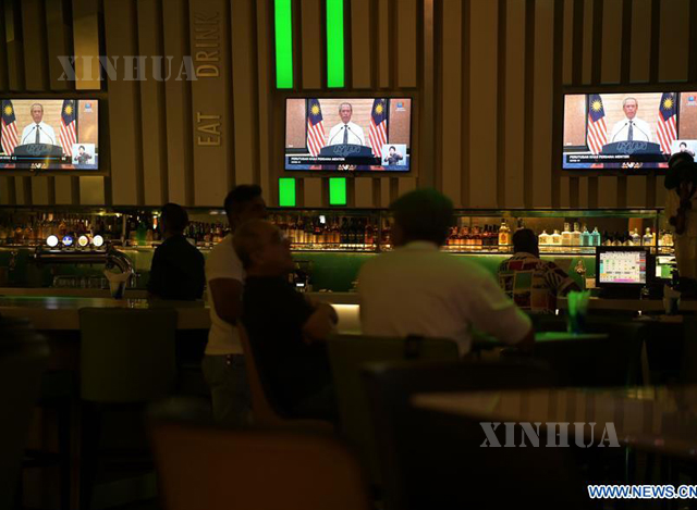 မလေးရှားနိုင်ငံ ကွာလာလမ်ပူမြို့ရှိ စားသောက်ဆိုင် တစ်ခုတွင် မတ် ၁၆ ရက်က တီဗွီမှ ထုတ်လွှင့်သော ဝန်ကြီးချုပ်မိန့်ခွန်းအား ကြည့်ရှုနားထောင်နေသူများအား တွေ့ရစဉ်(ဆင်ဟွာ)