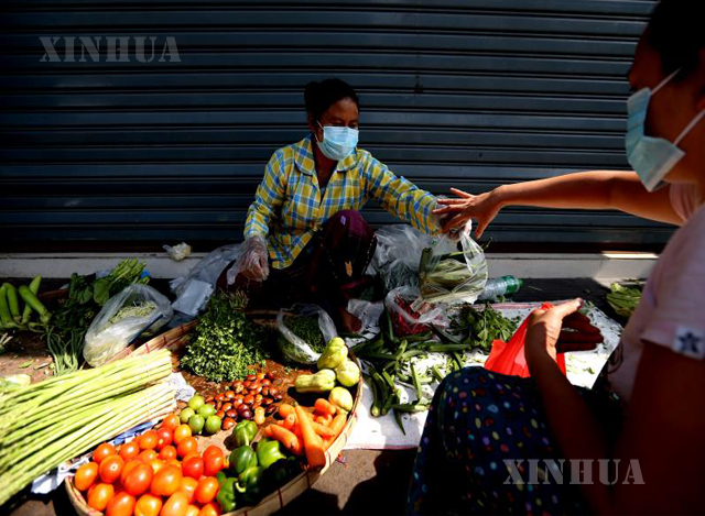 ရန်ကုန်မြို့၌ နှာခေါင်းစည်း တပ်ဆင်၍ ဈေးရောင်းနေသူ တစ်ဦးအား တွေ့ရစဉ်(ဆင်ဟွာ)