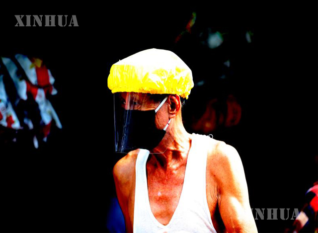 ရန်ကုန်မြို့၌ နှာခေါင်းစည်း နှင့် မျက်နှာ အကာအကွယ်များ တပ်ဆင်ထားသော အမျိုးသား တစ်ဦးအား တွေ့ရစဉ်(ဆင်ဟွာ)