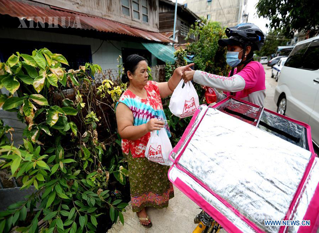 ရန်ကုန်မြို့တွင်း အစားအသောက်များအား စက်ဘီးစီးနင်း၍ လိုက်လံပို့ဆောင်ပေးနေသော မခင်မင်းသျှင်အား တွေ့ရစဉ်(ဆင်ဟွာ)