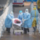 တရုတ်နိုင်ငံ ဝူဟန့်မြို့ရှိ ဟော်ဆန်ဆန်းဆေးရုံ၌ ဖေဖော်ဝါရီ ၄ ရက်တွင် ကျန်းမာရေးဝန်ထမ်းများက COVID-19 လူနာတစ်ဦအား လူနာတင်ယာဉ်မှ သယ်ထုတ်လာစဉ်(ဆင်ဟွာ)
