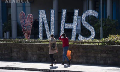 ဗြိတိန်နိုင်ငံ မန်ချက်စတာမြို့ Salford Royal ဆေးရုံ အပြင်ဘက်ရှိ Love NHS(National Health Service)သင်္ကေတရှေ့မှ ဖြတ်သန်းသွားလာကြသူများအား တွေ့ရစဉ်(ဆင်ဟွာ)