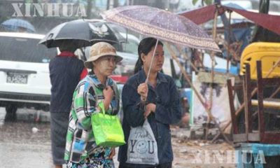 မိုးရွာသွန်းစဉ် ထီးဖြင့် သွားလာနေသူအချို့အားတွေ့ရစဉ် (ဆင်ဟွာ)