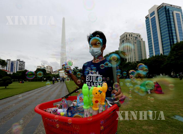 ရန်ကုန်မြို့မဟာဗန္ဓုလပန်းခြံအတွင်း နှာခေါင်းစည်း တပ်ဆင်၍ ဈေးရောင်းနေသူ တစ်ဦးအား တွေ့ရစဉ်(ဆင်ဟွာ)