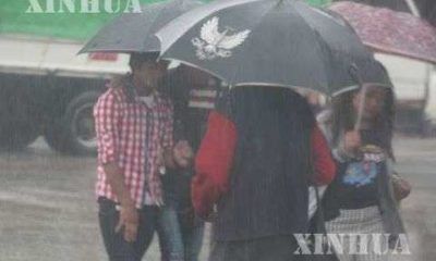 မိုးရေထဲတွင် ထီးဖြင့်သွားနေသူတချို့အားတွေ့ရစဉ် (ဆင်ဟွာ)