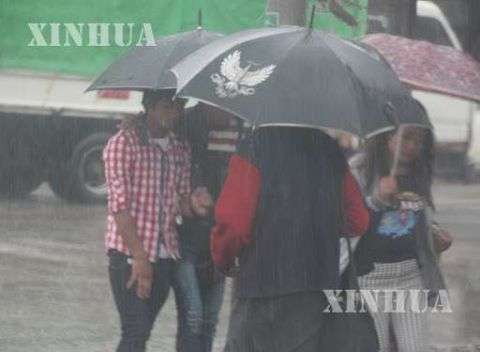 မိုးရေထဲတွင် ထီးဖြင့်သွားနေသူတချို့အားတွေ့ရစဉ် (ဆင်ဟွာ)