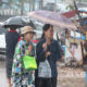 မိုးရေထဲတွင် ထီးဖြင့် သွားလာနေကြသူများအားတွေ့ရစဉ် (ဆင်ဟွာ)