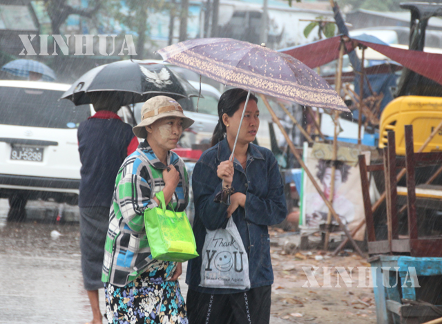 မိုးရေထဲတွင် ထီးဖြင့် သွားလာနေကြသူများအားတွေ့ရစဉ် (ဆင်ဟွာ)