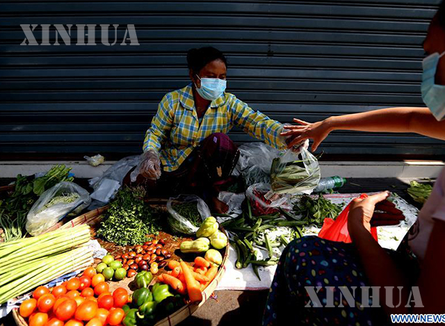 ရန်ကုန်မြို့၌ နှာခေါင်းစည်းတပ်၍ ဈေးရောင်းနေသူအားတွေ့ရစဉ်(ဆင်ဟွာ)