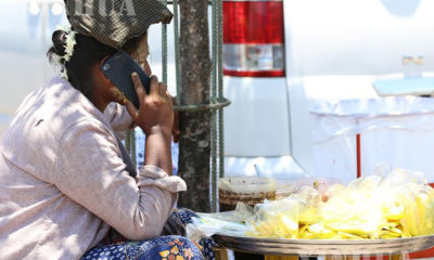 ရန်ကုန်မြို့၌ ဈေးရောင်းချနေသူတစ်ဦး မိုဘိုင်းလ်ဖုန်းဖြင့် စကားပြောနေစဉ် (ဆင်ဟွာ)