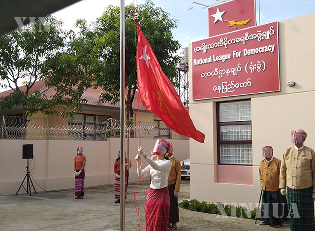အမျိုးသားဒီမိုကရေစီအဖွဲ့ချုပ်(NLD)ပါတီ ဥက္ကဋ္ဌဒေါ်အောင်ဆန်းစုကြည်က ပါတီ၏ အောင်နိုင်ရေးအလံကို လွှင့်တင်နေစဉ် (ဆင်ဟွာ)