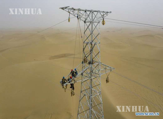 တရုတ်နိုင်ငံ အနောက်မြောက်ပိုင်း ရှင်းကျန်း (ဝေဂါ) ကိုယ်ပိုင်အုပ်ချုပ်ခွင့်ရဒေသ Hotan စီရင်စုရှိ လျှပ်စစ်တာဝါတိုင်တစ်ခုပေါ်တွင် အလုပ်လုပ်နေသူများကို တွေ့ရစဉ် (ဆင်ဟွာ)