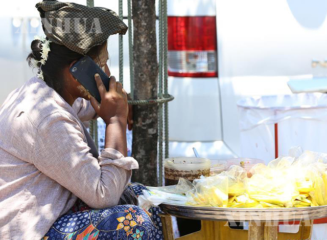 ရန်ကုန်မြို့၌ ဈေးရောင်းနေသူ တစ်ဦး တယ်လီဖုန်းဖြင့် ဆက်သွယ်ပြောဆိုနေသည်ကို တွေ့ရစဉ်(ဆင်ဟွာ)