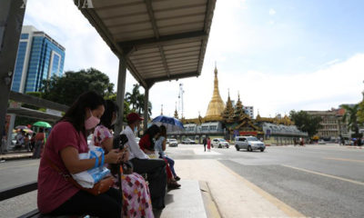 ရန်ကုန်မြို့ရှိ ဘတ်စ်ကားမှတ်တိုင်တစ်ခု တွင် ကားစီးရန် စောင့်ဆိုင်းနေသော ပြည်သူများအား တွေ့ရစဉ်(ဆင်ဟွာ)