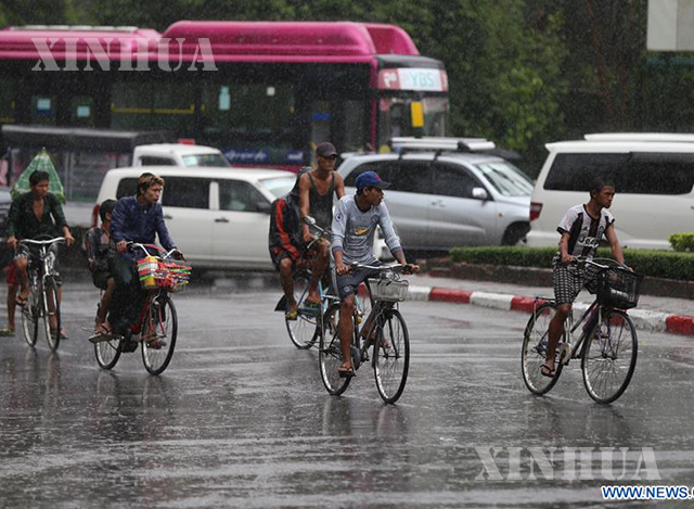 ရန်ကုန်မြို့တွင် မိုးသည်းထန်စွာရွာသွန်းပြီးနောက် စက်ဘီးဖြင့်သွားလာနေကြသူများအားတွေ့ရစဉ် (ဆင်ဟွာ)