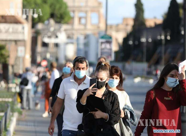 အီတလီနိုင်ငံ ရောမမြို့ရှိ Via dei Fori Imperiali လမ်းမပေါ်တွင် နှာခေါင်းစည်းတပ်ဆင်ကာ သွားလာနေသူများကို တွေ့ရစဉ် (ဆင်ဟွာ)