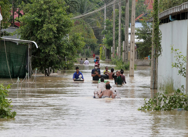 ကမ္ဘောဒီးယားနိုင်ငံ ဖနွမ်းပင်မြို့ အနောက်တောင်ဘက် Dangkor ခရိုင်တွင် ရေဖုံးလွှမ်းနေသည့် လမ်းပေါ်၌ သွားလာနေသူများကို တွေ့ရစဉ် (ဓာတ်ပုံ- Phearum/Xinhua)