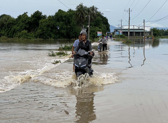 ဗီယက်နမ်နိုင်ငံ အလယ်ပိုင်း Ninh Thuan ပြည်နယ်တွင် မိုးသည်းထန်စွာရွာသွန်းမှုကြောင့် ရေဖုံးလွှမ်းနေသည့်လမ်းပေါ်တွင် ဖြတ်သန်းသွားလာနေသူများကို တွေ့ရစဉ် (ဓာတ်ပုံ - VNA via Xinhua)