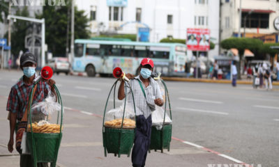 ရန်ကုန်မြို့၌ နှာခေါင်းစည်း တပ်ဆင်၍ ဈေးရောင်းသွားလာနေသူ နှစ်ဦးအား တွေ့ရစဉ်(ဆင်ဟွာ)
