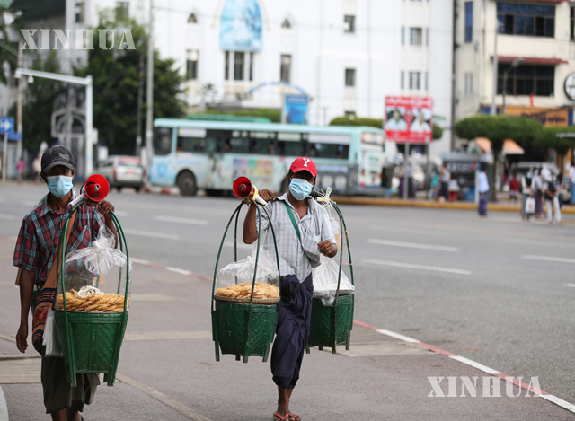 ရန်ကုန်မြို့၌ နှာခေါင်းစည်း တပ်ဆင်၍ ဈေးရောင်းသွားလာနေသူ နှစ်ဦးအား တွေ့ရစဉ်(ဆင်ဟွာ)