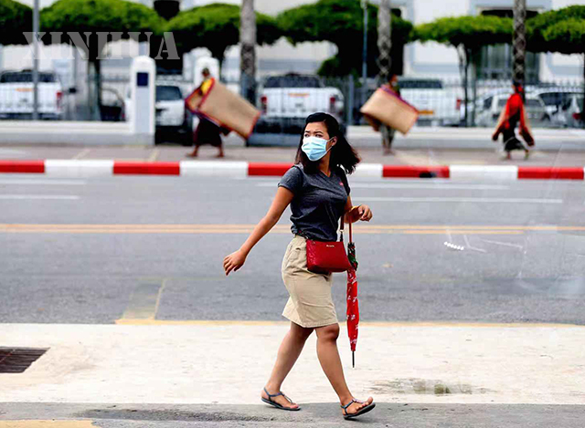 ရန်ကုန်မြို့ မဟာဗန္ဓုလပန်းခြံအတွင်း နှာခေါင်းစည်း တပ်ဆင်၍ ဈေးရောင်းနေသူ တစ်ဦးအား တွေ့ရစဉ်(ဆင်ဟွာ)