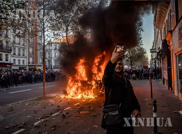 ပြင်သစ်နိုင်ငံ ပါရီမြို့တွင် အမျိုးသားတစ်ဦးက ဆန္ဒပြမှုအတွင်း မီးရှို့ခံရသည့် မော်တော်ယာဉ်အရှေ့၌ ဓါတ်ပုံရိုက်နေသည်ကို နိုဝင်ဘာ ၂၈ ရက်က တွေ့ရစဉ်(ဆင်ဟွာ)