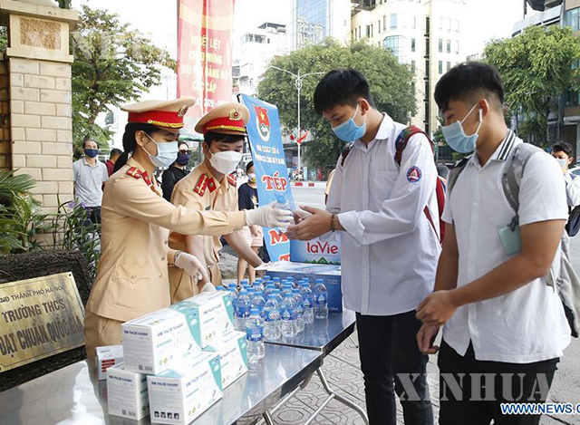 ဗီယက်နမ်နိုင်ငံ ဟနွိုင်းမြို့တွင် ဩဂုတ်၉ ရက်က အထက်တန်းကျောင်းစာမွေးပွဲသွားရောက်ဖြေဆိုမည့် ကျောင်းသားကျောင်းသူများကို ယာဉ်ထိန်းရဲများက ရေသန့်ဗူး ဝေငှပေးနေစဉ်(ဆင်ဟွာ)