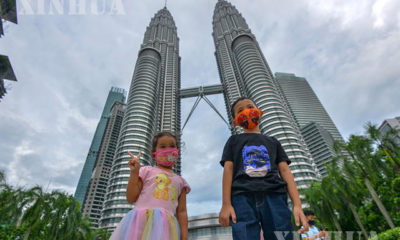 မလေးရှားနိုင်ငံ ကွာလာလမ်ပူမြို့အမွှာမျှော်စင်ရှေ့တွင် ဓာတ်ပုံရိုက်နေသော ကလေးငယ်နှစ်ဦးအား အောက်တိုဘာ ၃ ရက်က တွေ့ရစဉ်(ဆင်ဟွာ)