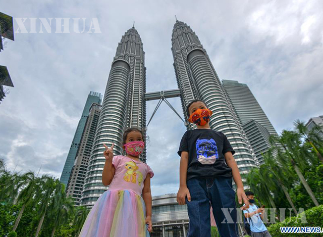 မလေးရှားနိုင်ငံ ကွာလာလမ်ပူမြို့အမွှာမျှော်စင်ရှေ့တွင် ဓာတ်ပုံရိုက်နေသော ကလေးငယ်နှစ်ဦးအား အောက်တိုဘာ ၃ ရက်က တွေ့ရစဉ်(ဆင်ဟွာ)