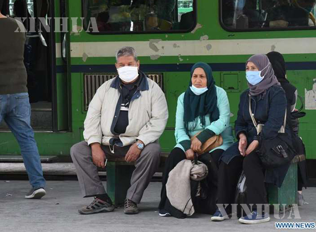 တူနီးရှားနိုင်ငံ တူးနစ်မြို့လယ်ရှိ ဘတ်စ်ကားမှတ်တိုင်တစ်ခုတွင် နှာခေါင်းစည်းတပ်ဆင်ထားသူများကို တွေ့ရစဉ် (ဆင်ဟွာ)