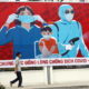 ဗီယက်နမ်နိုင်ငံ ဟနွိုင်းမြို့၌ COVID-19 ရောဂါတိုက်ဖျက်ရေး ပိုစတာရှေ့တွင် လမ်းလျှောက်နေသူတစ်ဦးအား တွေ့ရစဉ်(VNA/Handout via Xinhua)
