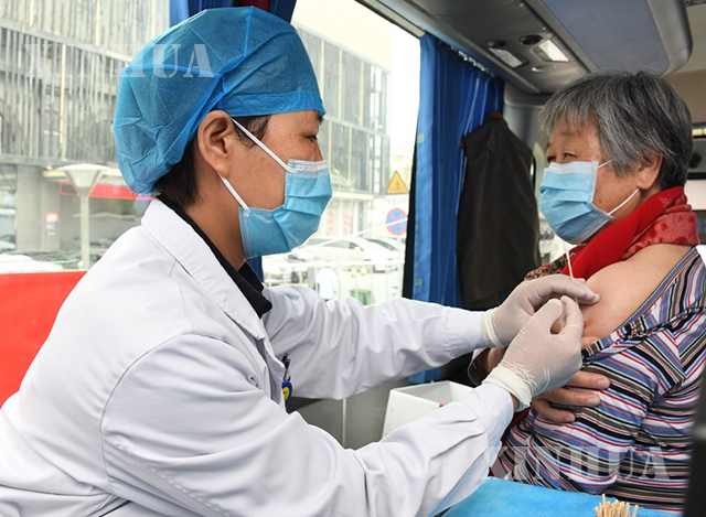 တရုတ်နိုင်ငံ ပေကျင်းမြို့၌ ကျန်းမာရေးဝန်ထမ်းတစ်ဦးက ရွေ့လျားကာကွယ်ဆေးထိုးယာဉ်ဖြင့် ကာကွယ်ဆေး လိုက်လံထိုးပေးနေသည်ကိုတွေ့ရစဉ်(ဆင်ဟွာ)