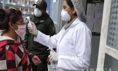 ဘိုလီးဗီးယားနိုင်ငံ လာပါဇ်မြို့ရှိ Hospital del Torax ဆေးရုံအတွင်း ဝင်ရောက်မည့် အမျိုးသမီးတစ်ဦးအား သူနာပြုတစ်ဦးက ကိုယ်အပူချိန်တိုင်းတာနေသည်ကိုတွေ့ရစဉ် (ဆင်ဟွာ)