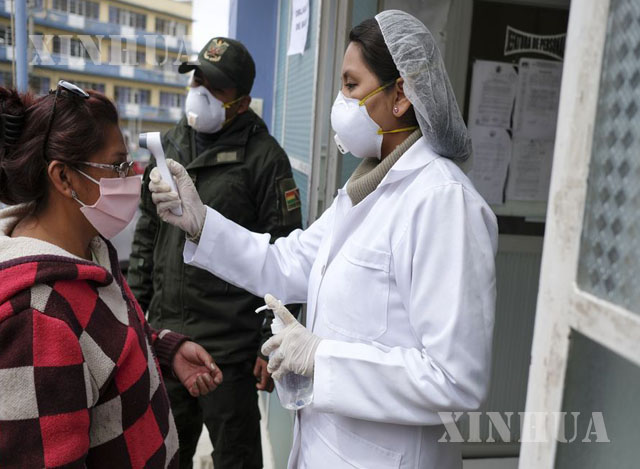 ဘိုလီးဗီးယားနိုင်ငံ လာပါဇ်မြို့ရှိ Hospital del Torax ဆေးရုံအတွင်း ဝင်ရောက်မည့် အမျိုးသမီးတစ်ဦးအား သူနာပြုတစ်ဦးက ကိုယ်အပူချိန်တိုင်းတာနေသည်ကိုတွေ့ရစဉ် (ဆင်ဟွာ)